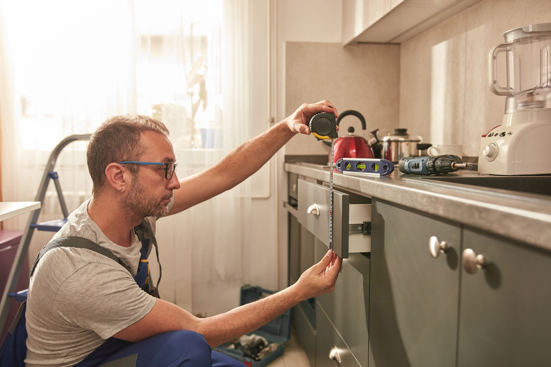 Handyman fixing kitchen cabinets in the apartment.