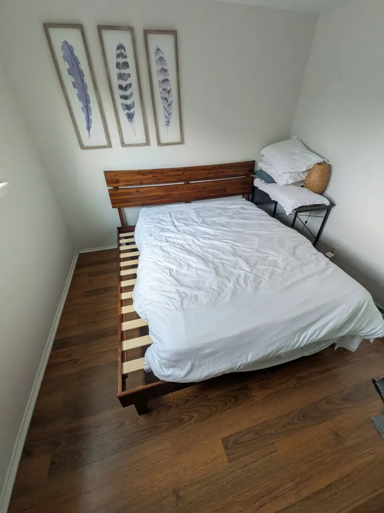 Wood platform bed frame assembled in a small bedroom