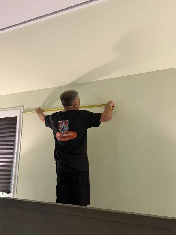 Gold Hands technician measuring a wall before an installation