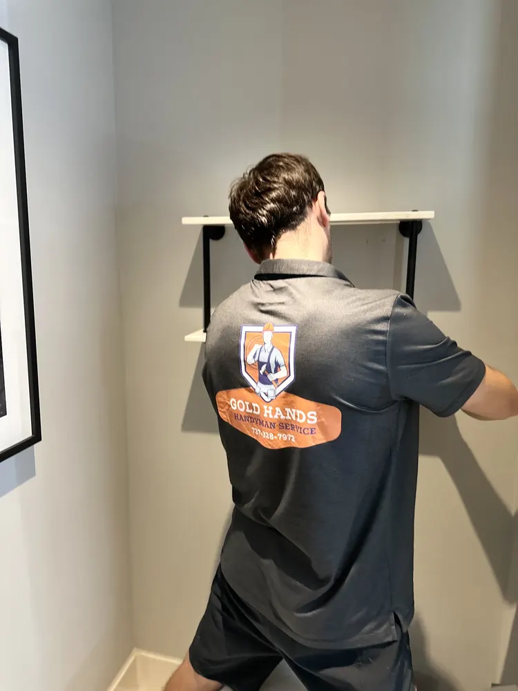 Gold Hands technician installing wall shelves
